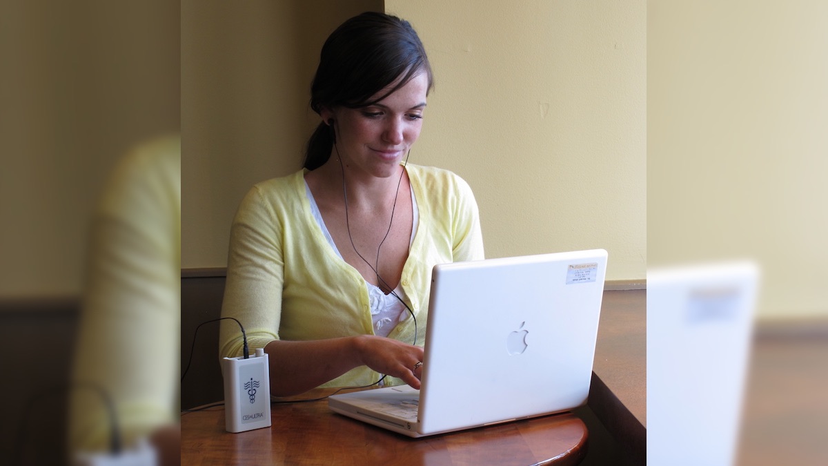 Person using a CES Ultra device to relax and increase focus while using a laptop computer